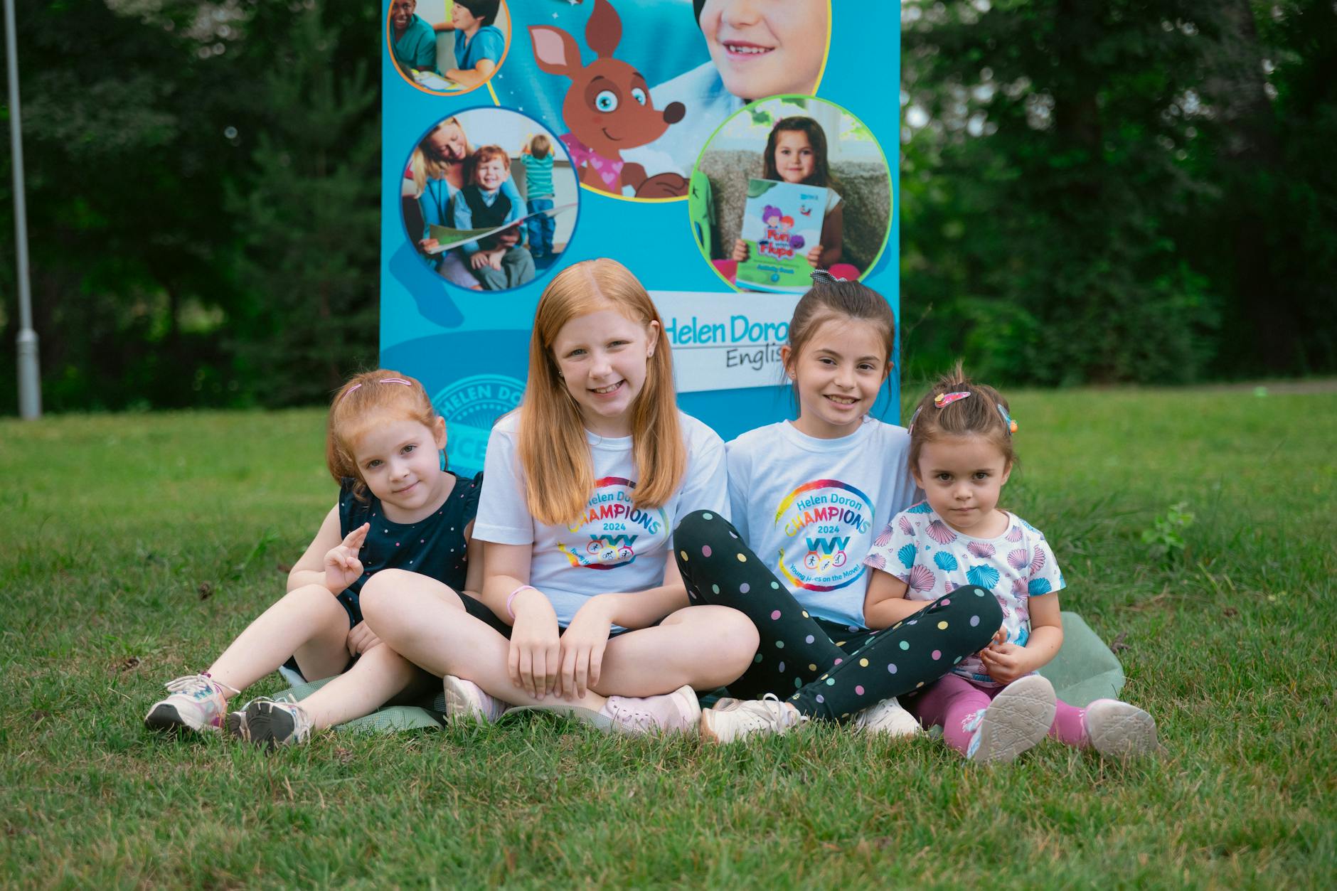 four girls sitting together on grass